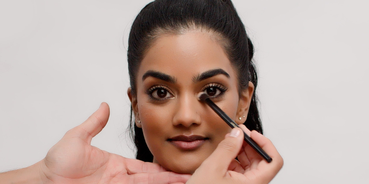 Makeup artist applying highlighter to the inner corner of our model’s eyes